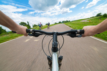 Fototapeta na wymiar Rider driving bicycle on an asphalt road. Two hand on bike handlebar. Motion blurred background