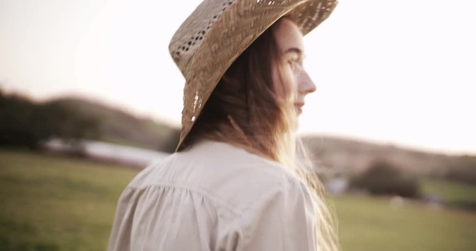 Attractive young woman with straw hat walking in a farm