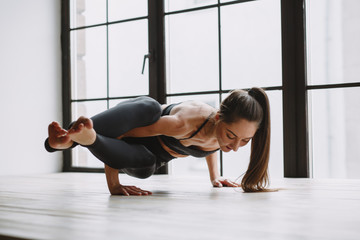 Fototapeta premium Young woman doing yoga at light window