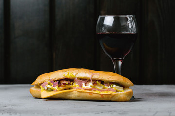 Hot dog and a glass of wine on a concrete background.