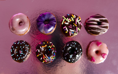 Eight delicious mini donuts, top view on reflected surface 
