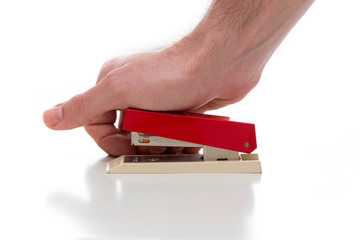 Stapler used by a male hand against a white background