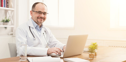 Portrait of doctor in glasses sitting at desktop