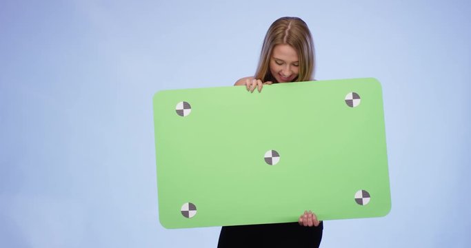Cheerful Woman holding oversized blank Card on blue Background