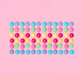 Assorted colored candies on pink background.