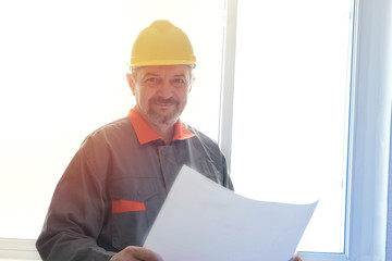 Engineer builder in a helmet on the object with a plan in hands toned photo portraite