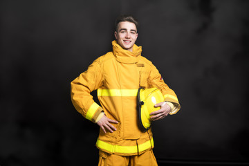 Portrait of the fireman standing Waist up studio shot on black background and moke.