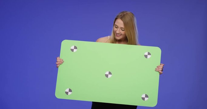 Stunning beautiful Woman holding blank oversized Card with Bluescreen Background