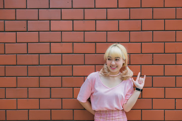 Portrait of thai woman golden hairs japan style on orange brick wall,Asian girl pose for take a picture outdoor