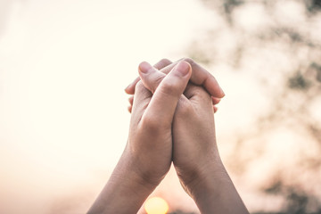 Human hands praying on nature during sunset,  hope and wish concept