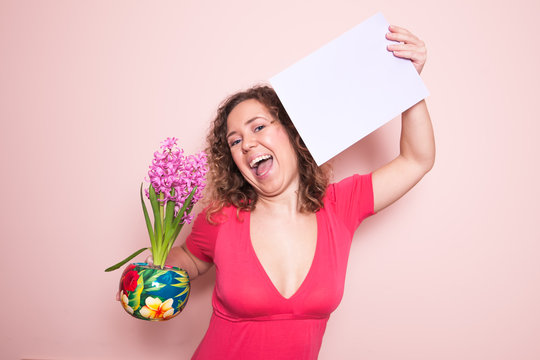 Happy beautiful curly woman holding empty mint blank board on pink background. Colorful studio portrait.