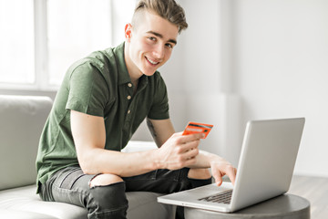 Handsome man using a laptop sitting on couch at home