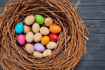 Top view of wicker nest with Easter eggs on wooden planks