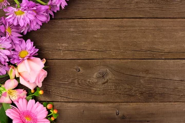 Rolgordijnen Gerbera Side border of pink and purple flowers with rose, daisies and lilies against a rustic wood background. Copy space.