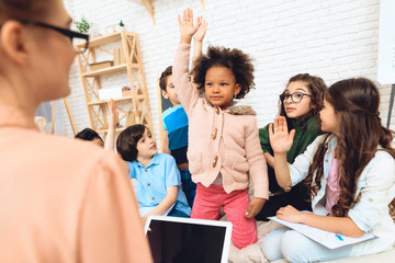 Group of children are pulling hands to answer teacher's question in primary school.