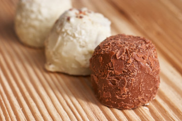 Macro. White and milk chocolate candies on a light wooden background