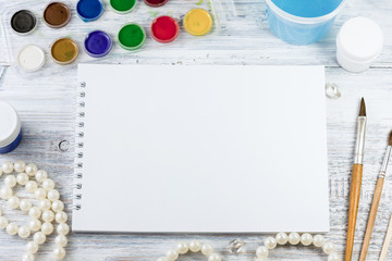 Mock up. Creative space. Artist workspace on vintage wooden table: watercolor, white paper, paint brushes,water and beads