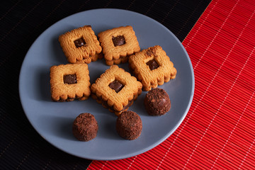 Stacked chocolate chip cookies on gray style plate on red and black wooden table