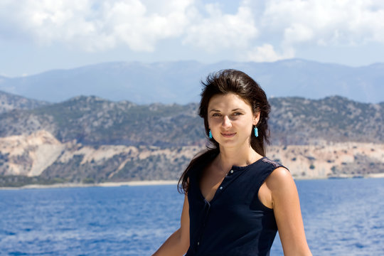 Beautiful brunette woman in a navy blue dress aboard a yacht in Turkey