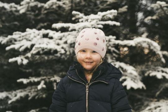 Portrait of cute girl wearing warm clothing while standing against snow covered tree