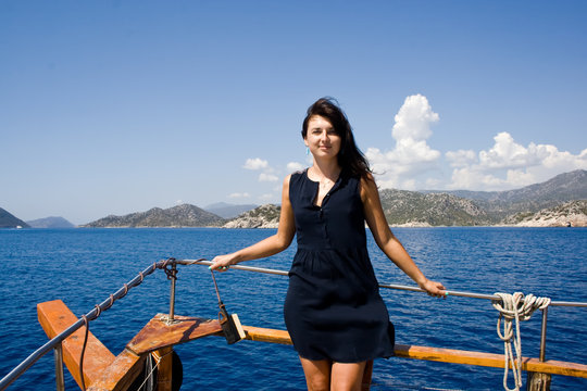 Beautiful brunette woman in a navy blue dress aboard a yacht in Turkey