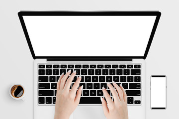 Hands typing on laptop with white isolated screen surrounded with coffee and smartphone. Top view. Mock-up