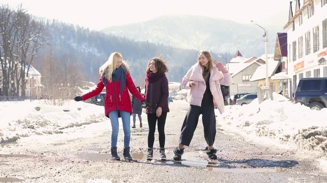 Happy women friends walking at city street in slow motion, mountains on background