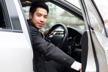 Young businessman open the door of his car.