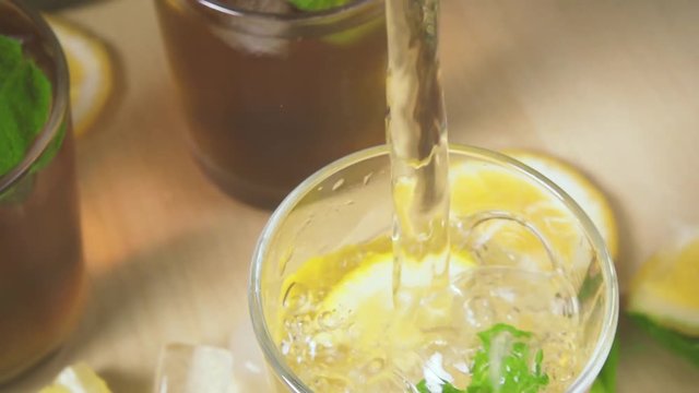 Slow motion tea with ice and mint in a glass and movement of the camera on a stream of water in a glass with ice and mint.