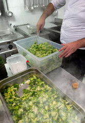Chef prepares green broccoli in a restaurant kitchen