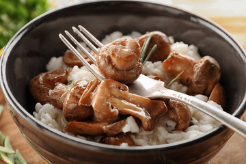 Bowl with risotto and mushrooms on table, closeup
