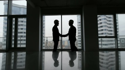 Partnership concept: two man silhouette handshake