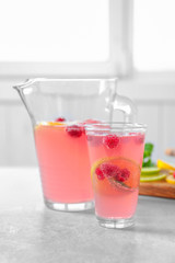 Jug and glass of fresh lemonade with berries on table