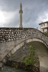 old arch bridge and minaret of the Koski Mehmed Pasha Mosque in Unesco area of old town Mostar,...