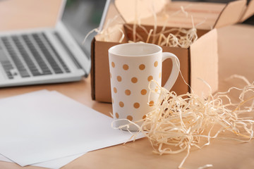 Open parcel box with cup on table in home office