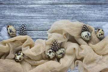 Easter decoration with quail eggs beige fabric gray wooden background.