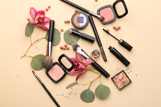 Decorative cosmetics and brushes of professional makeup artist on color background