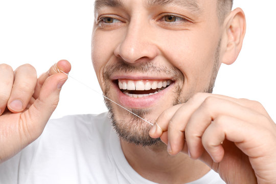 Young man flossing his teeth on white background