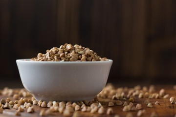 Buckwheat grain on ceramic bowl over wooden table.
