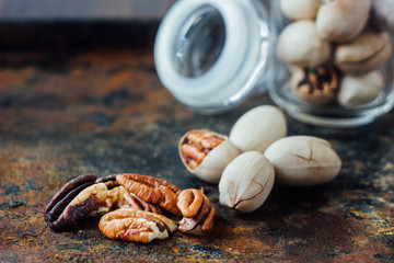 Pecan nuts inside glass jar on rustic surface.