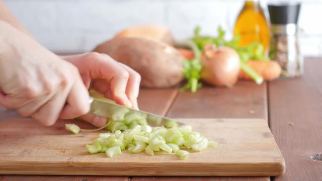 cutting, chopping celery on a wooden board