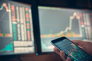 Young male trader at office work concept sitting with smartphone close-up