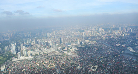 Fototapeta na wymiar A view of the city of Manila through the window from the plane. Impressed photo of a tourist in flight over the capital. Philippines.