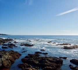 Beautiful scenic coastal view in California (USA): Untouched nature of the pacific ocean with limestone rock cliffs and crashing waves with a clear blue summer sky create the perfect picturesque place