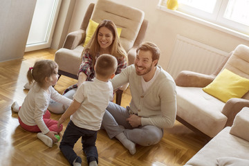 Parents with children playing together and having fun in living room
