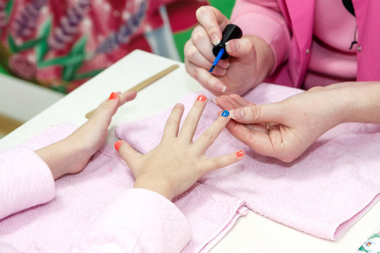 Close up of pretty young woman painting nails with her girlfrien