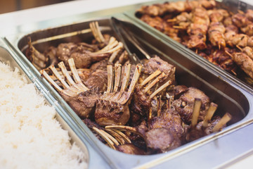 Beautifully decorated catering banquet table with different main course hot food dishes and garnish, with rice, chicken, lamb, vegetables and kebab on corporate party event or wedding celebration