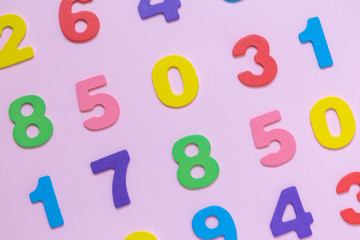 Multicolored wooden numbers texture on pastel rose background minimalistic concept.