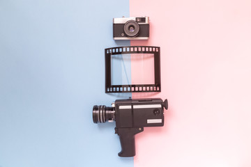 Flat lay of old fashioned camcorder, camera and photo frame against pastel background minimalistic concept.