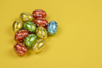 Chocolate easter eggs foil on yellow background.